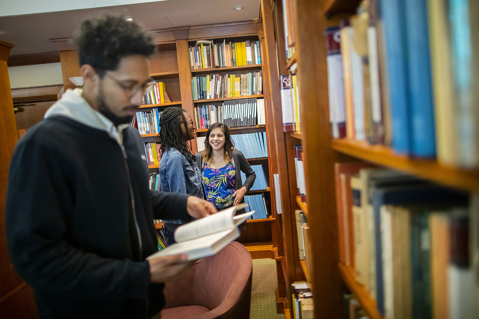Three postdocs in a library, shallow depth of field.